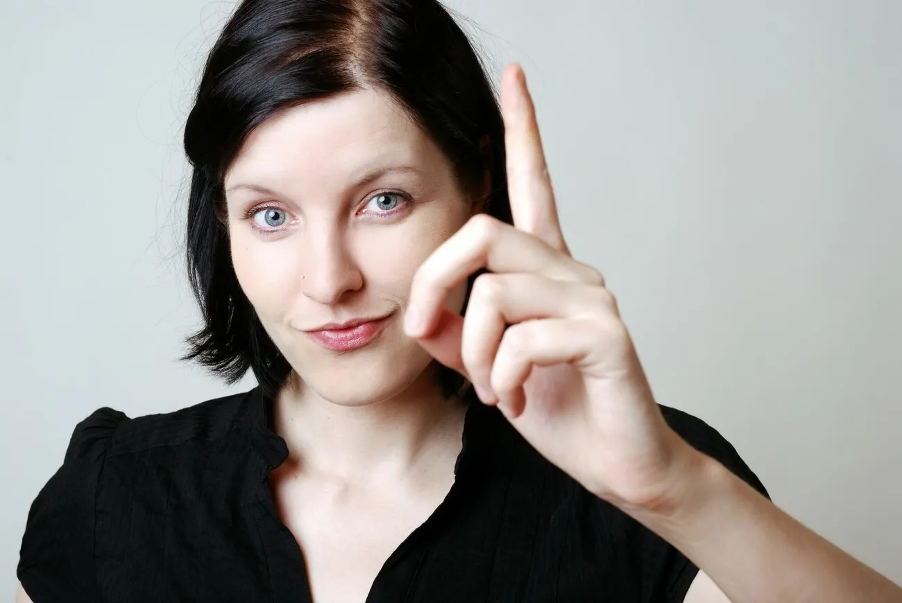 Frau erhebt ihren Zeigefinger.