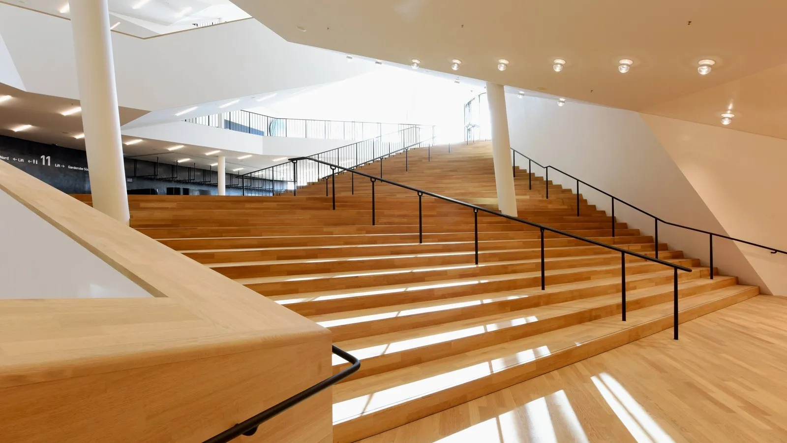 Das Foyer der Elbphilharmonie. Mehrere Treppenstufen, beleuchtete weiße Decke.