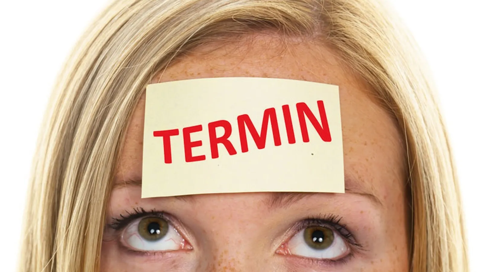 Eine blonde Frau mit einem Notizzettel mit der Aufschrift "Termin" auf der Stirn.