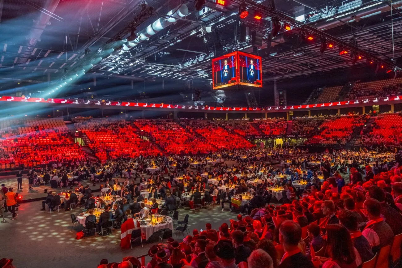 Ein Blick auf die breite Menschenmasse bei der Abschlusszeremonie und Siegerehrung bei den EuroSkills 2025 in Herning. Die Leute in der Mitte sitzen an runden dekorierten Tischen.