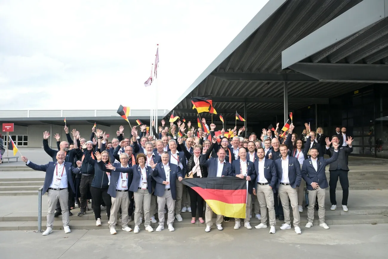 Ein Gruppenfoto der Teilnehmer und Teilnehmerinnen. Es werden drei Deutschland-Flaggen geschwungen.