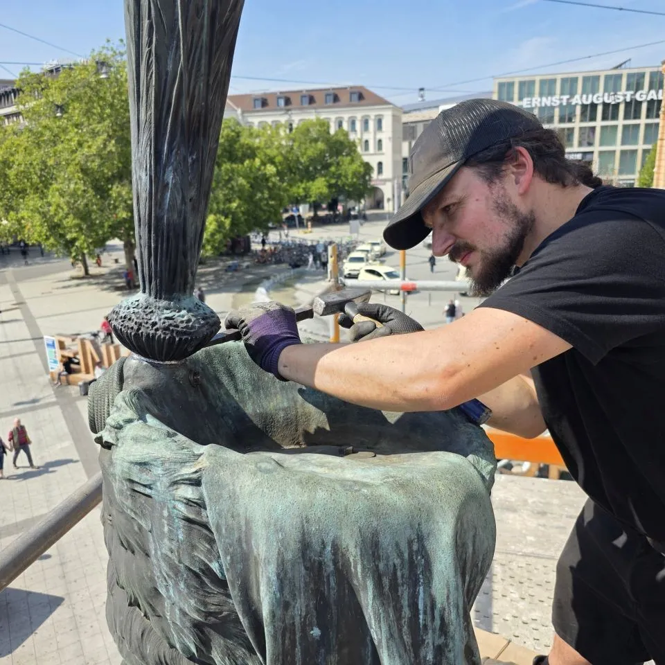 Jungmeister Matthies Wesche beim Verstemmen der Bleieinfassung des Federbusches bei der Wiedermontage