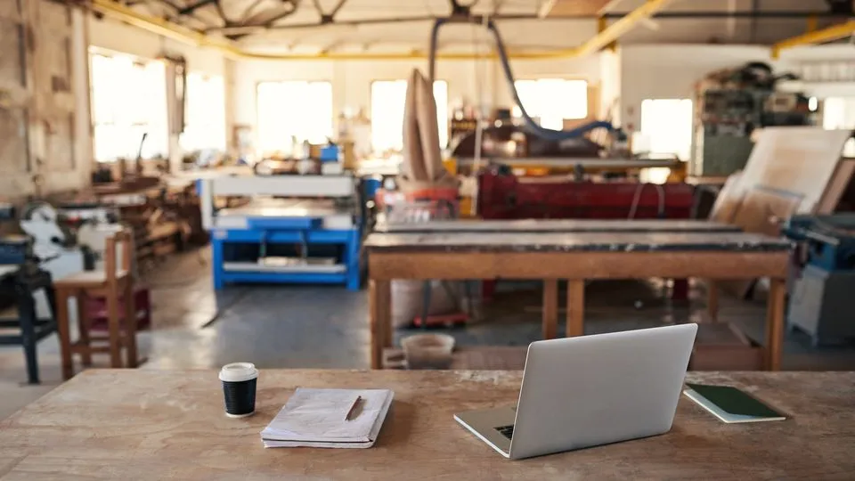 Latop und Kaffee auf der Werkbank in der Werkstatt ohne Handwerker