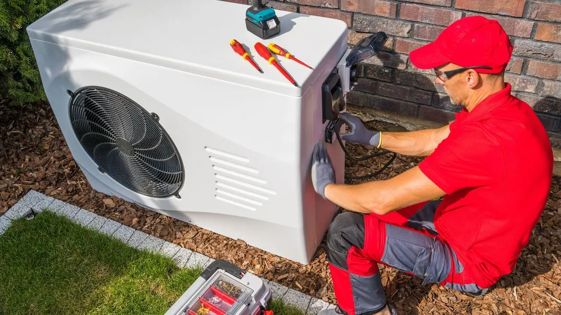Ein Handwerker baut eine Wärmepumpe ein.