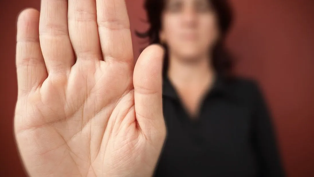 Frau sagt stop
Woman with her hand extended signaling to stop (only her hand is in focus) on a red background