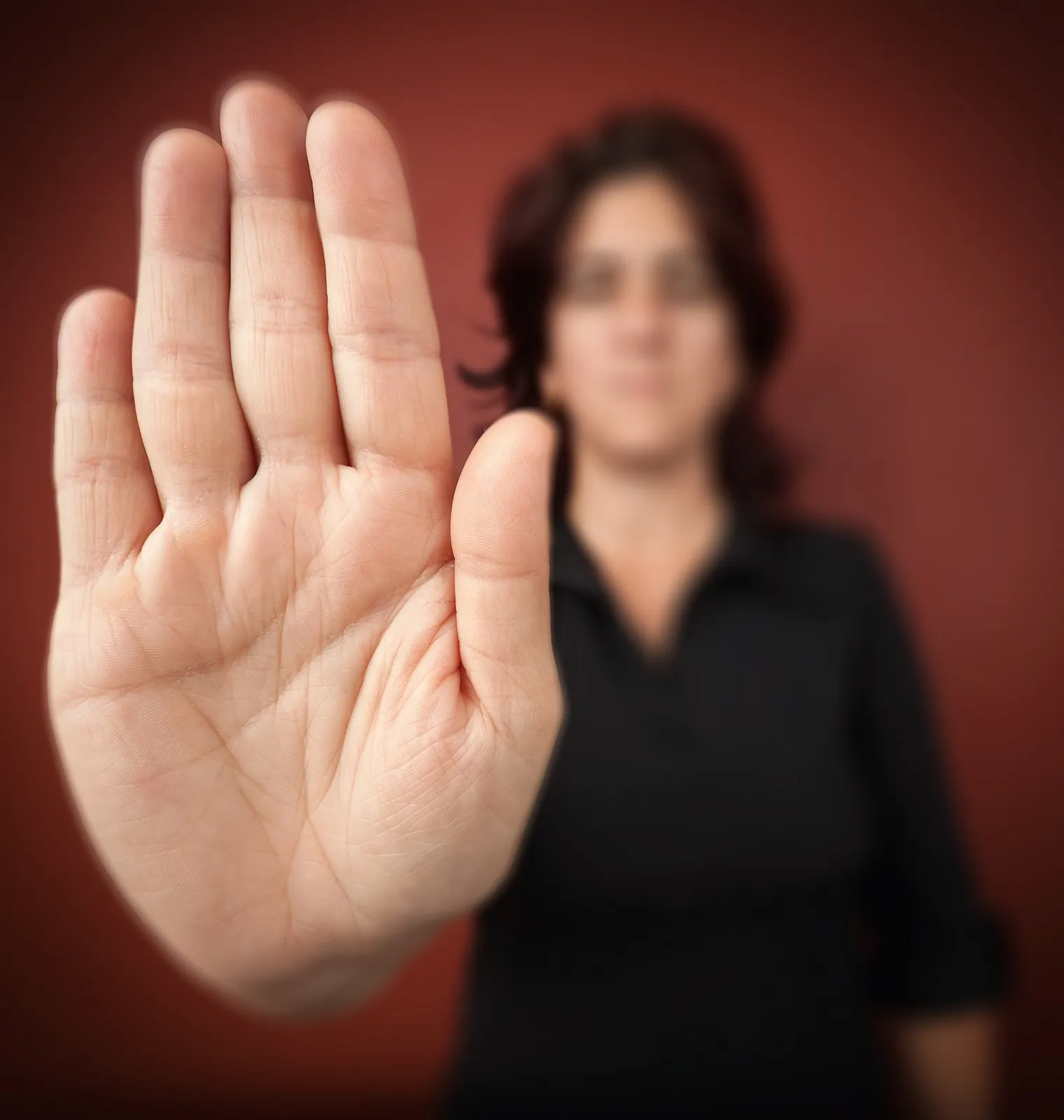 Eine Frau hält ihre Hand ausgestreckt in die Kamera und signalisiert damit ein "Stopp".