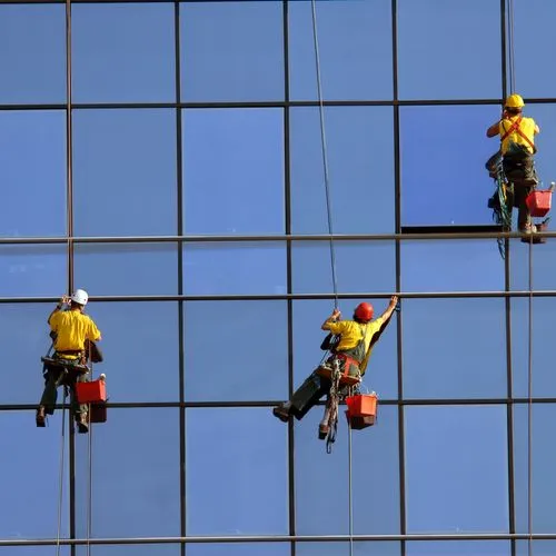 Drei Gebäudereiniger reinigen die Fenster einer Glasfassade