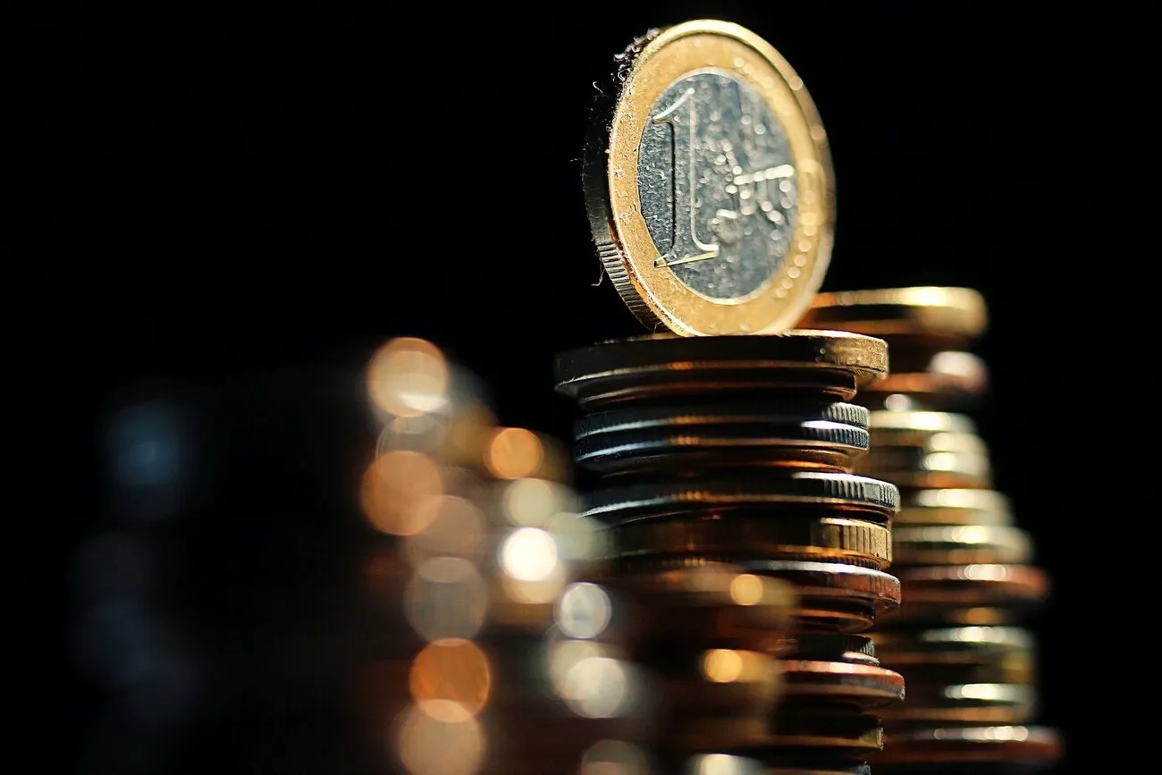 Eine funkelnde 1-Euro-Münze thront auf einem Münzstapel.