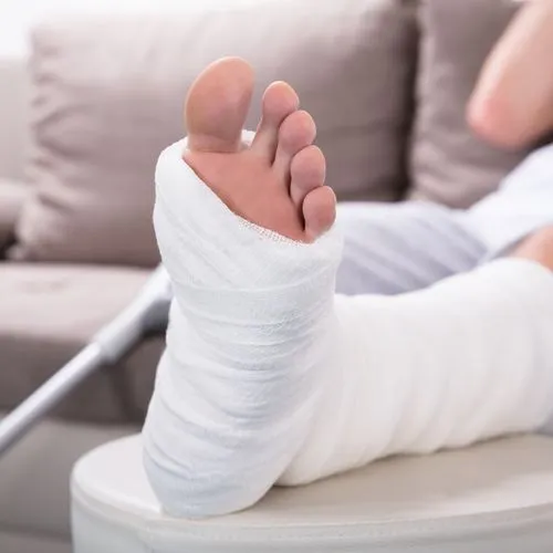 Ein Mann sitzt auf einem Sofa und hat sein gegipstes Bein hochgelegt.