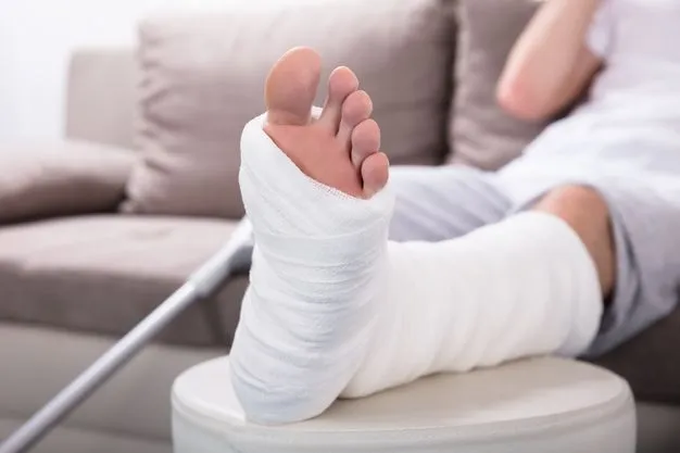 Ein Mann sitzt auf einem Sofa und hat sein gegipstes Bein hochgelegt.