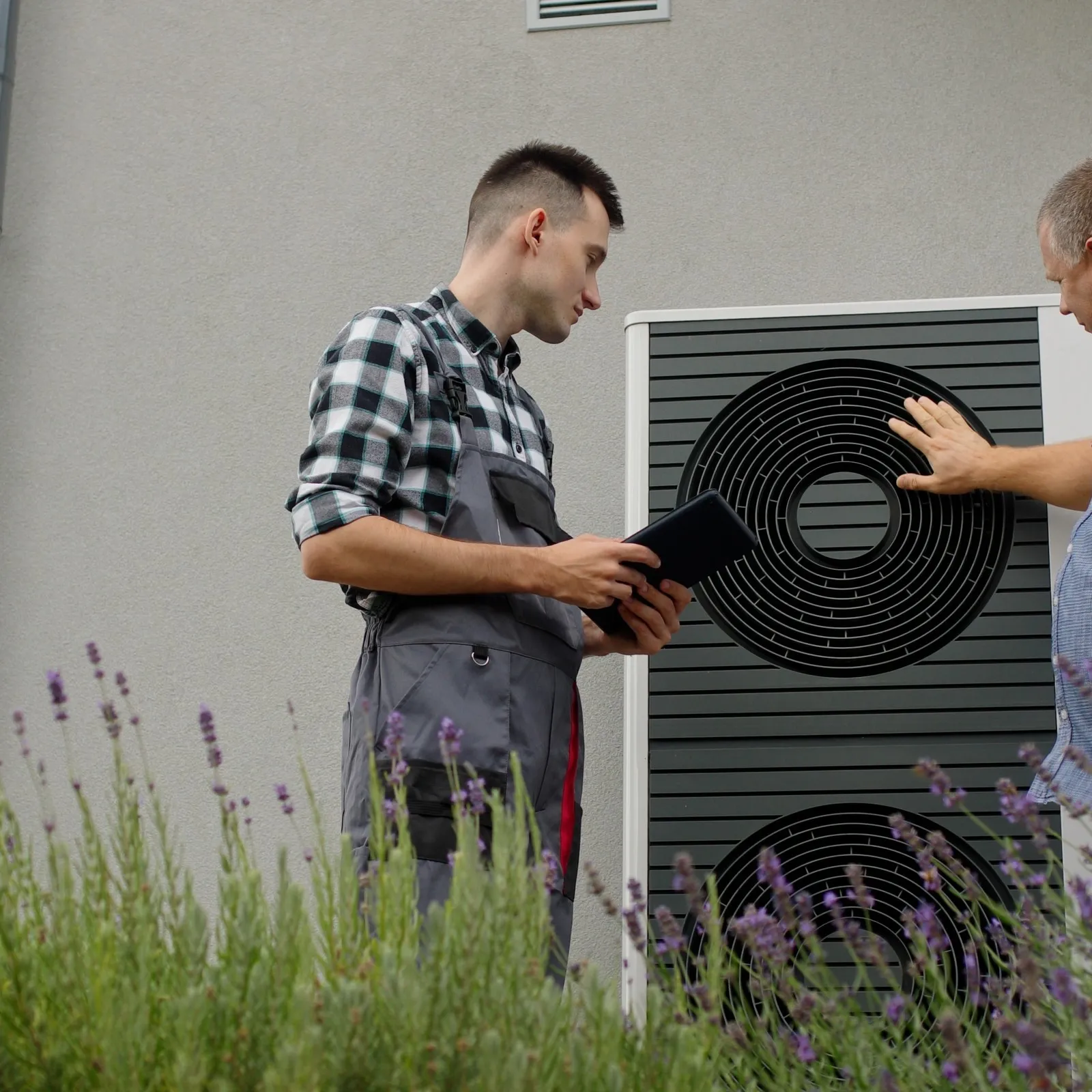 Handwerker und Hausbesitzer im Gespräch an einer Wärmepumpe