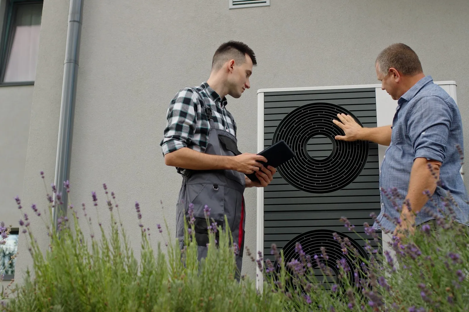 Handwerker und Hausbesitzer im Gespräch an einer Wärmepumpe