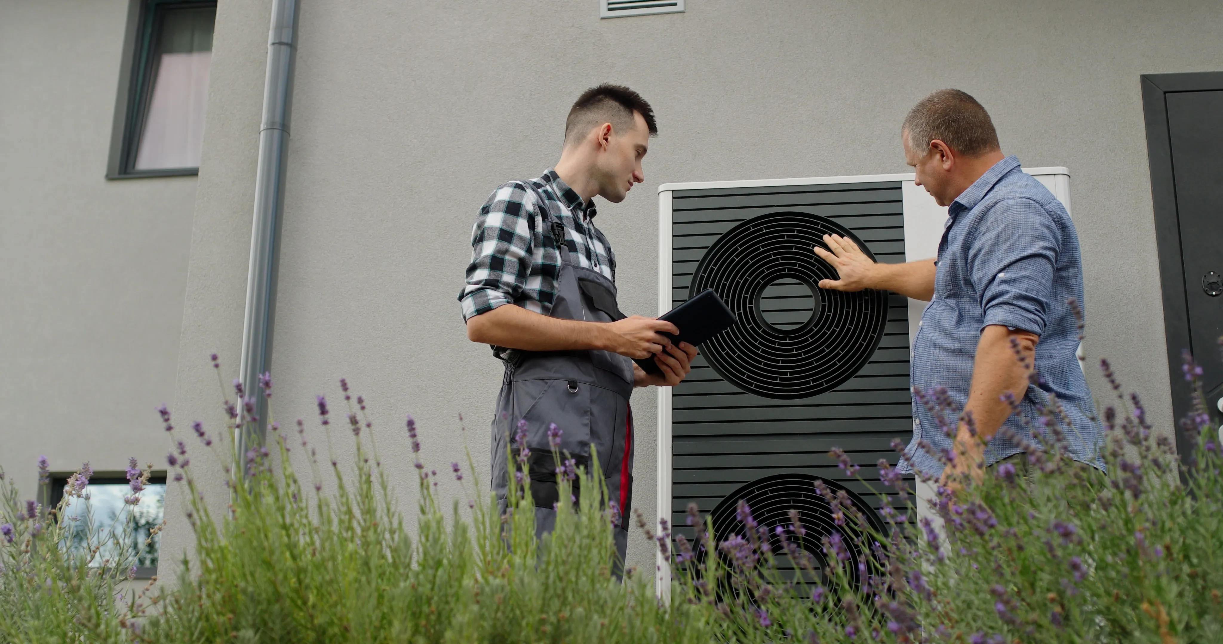 Handwerker und Hausbesitzer im Gespräch an einer Wärmepumpe