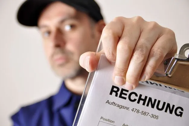 Ein Handwerker mit einer schwarzen Cap hält eine Rechnung ins Bild.