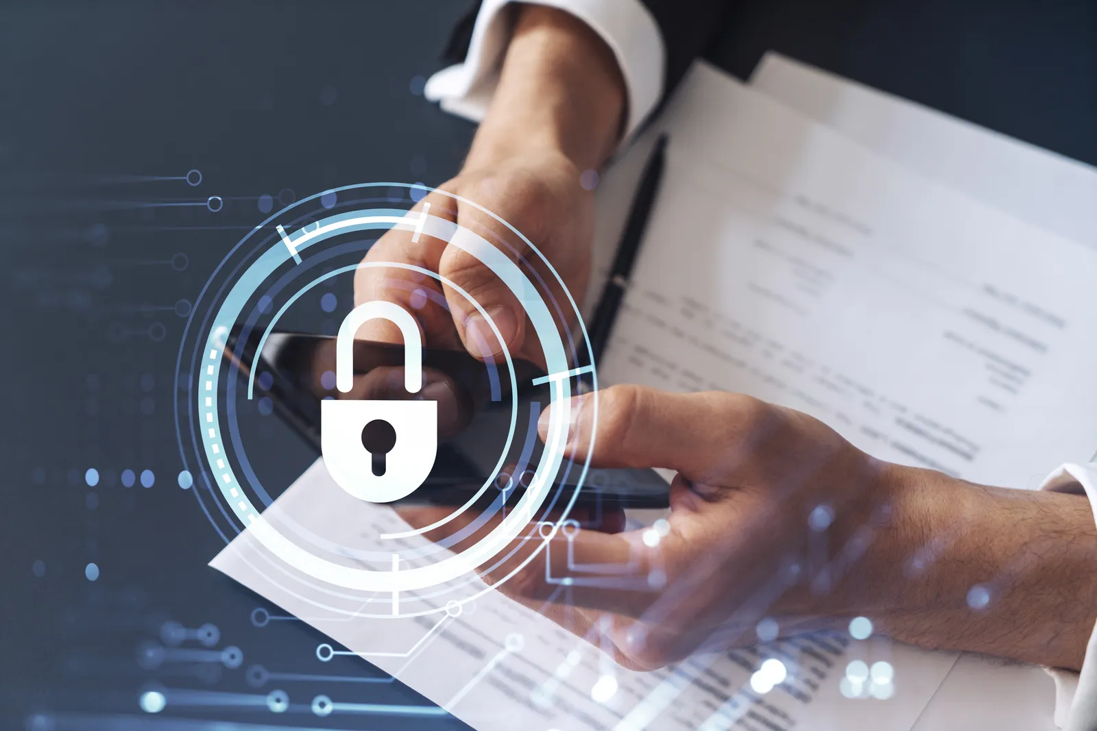 Ein Geschäftsmann in formeller Kleidung liest einen Vertrag, um Risiken im Bereich der Cybersicherheit vorzubeugen, und überprüft Details auf seinem Smartphone. Über dem Schreibtisch sind Hologramm-Symbole in Form von Vorhängeschlössern zu sehen.