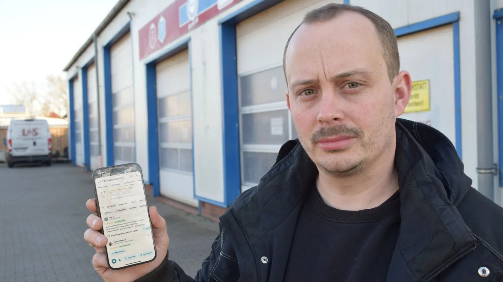 Foto von Hannes Liebenow, der ein Smartphone hochhält.