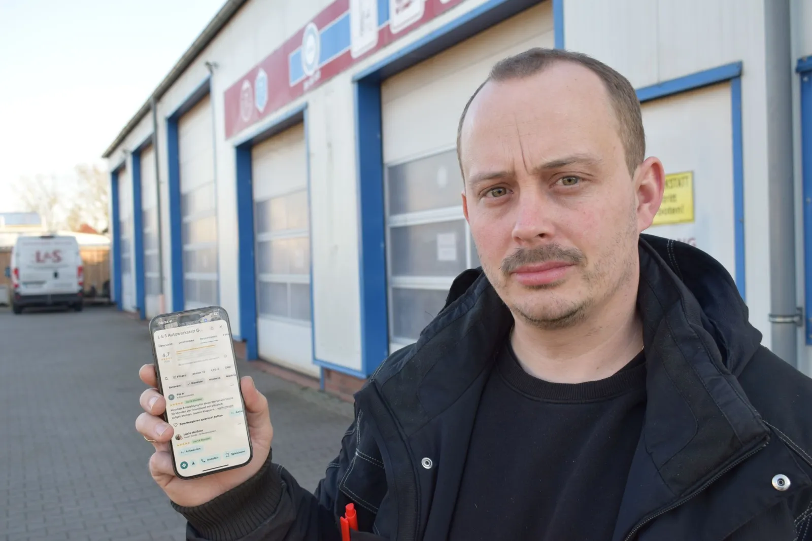 Foto von Hannes Liebenow, der ein Smartphone hochhält.
