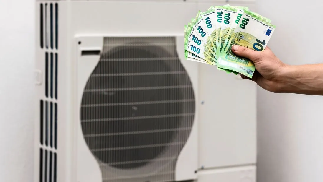 Wärmepumpe: Jemand hält eine Hand mit diversen 100-Euro-Scheinen vor das Gerät.