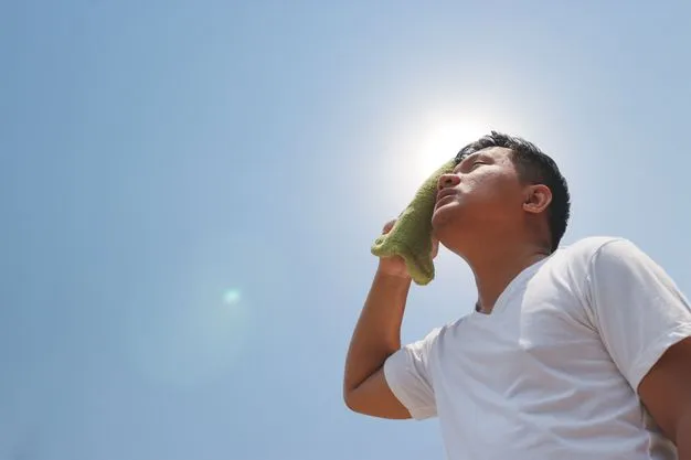 Die Sonne scheint umd ein Mann wischt sich den Schweiß von der Stirn.