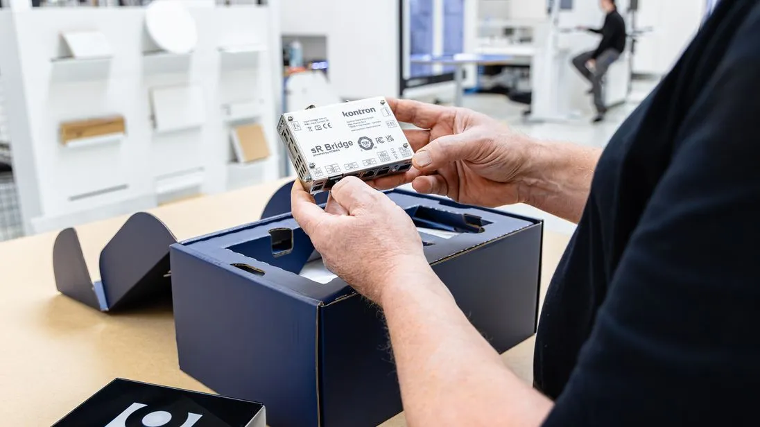 Ein blauer Karton darüber hält ein Mann die serviceRemote Bridge von Homag.