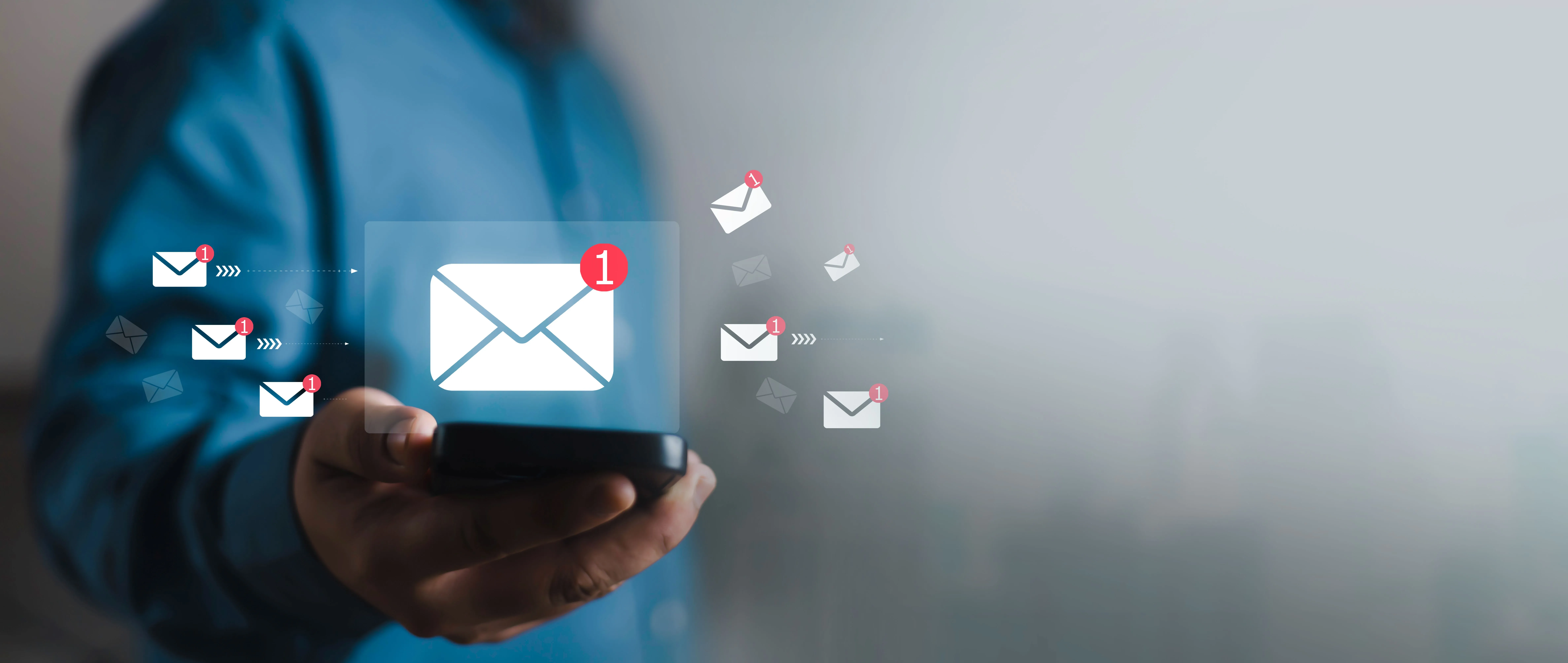 Ein Mann hält ein Smartphone in der Hand. Darüber ist virtuell eine E-Mail eingeblendet.