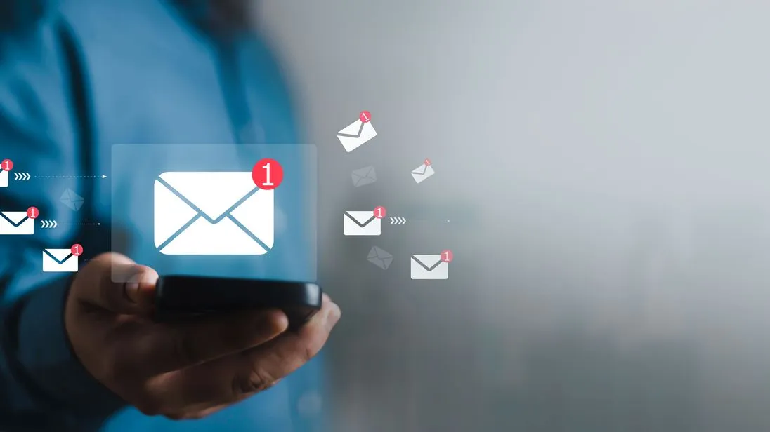 Mann hält ein Handy hoch, darüber wird eine virtuelle E-Mail angezeigt.