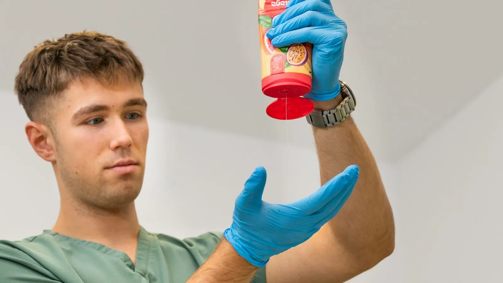 Bauer drückt Duschgel aus einer Flasche auf seine Hand, die von einem Handschuh geschützt wird.