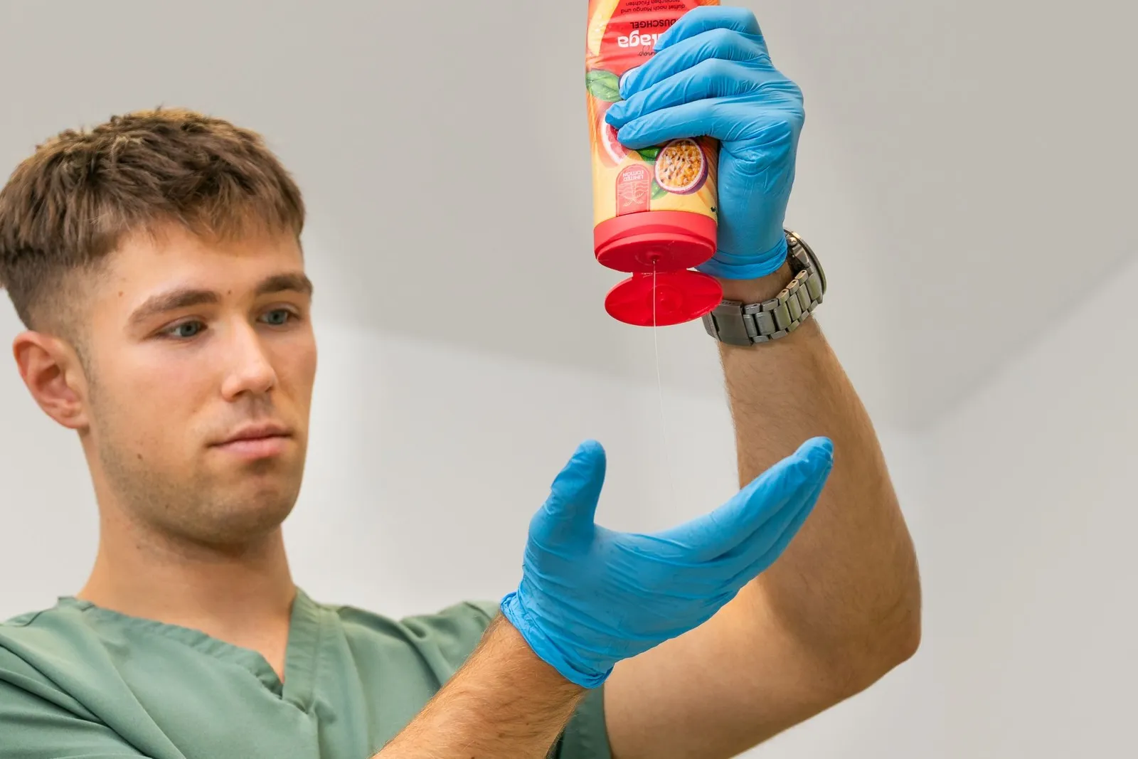 Bauer drückt Duschgel aus einer Flasche auf seine Hand, die von einem Handschuh geschützt wird.