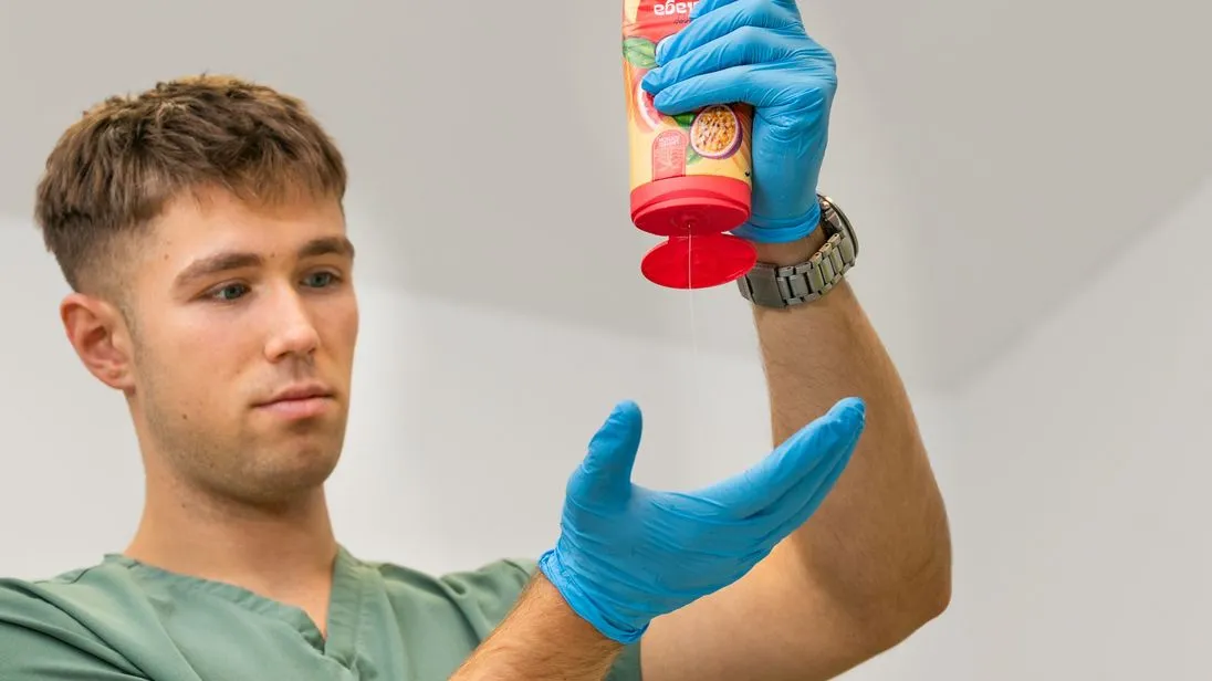 Bauer drückt Duschgel aus einer Flasche auf seine Hand, die von einem Handschuh geschützt wird.