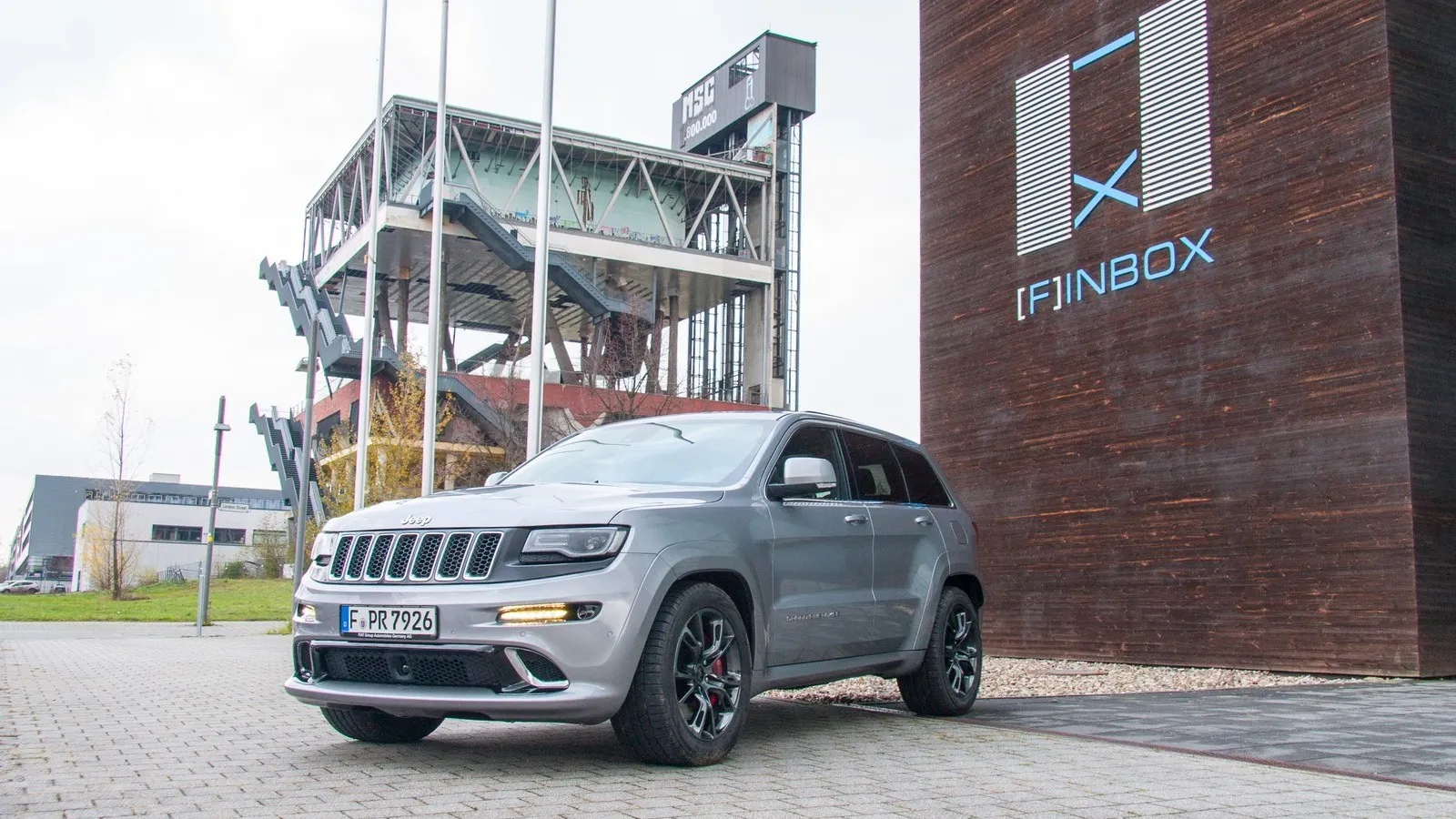 Der silberne Jeep Grand Cherokee SRT steht vor einem Gebäude.