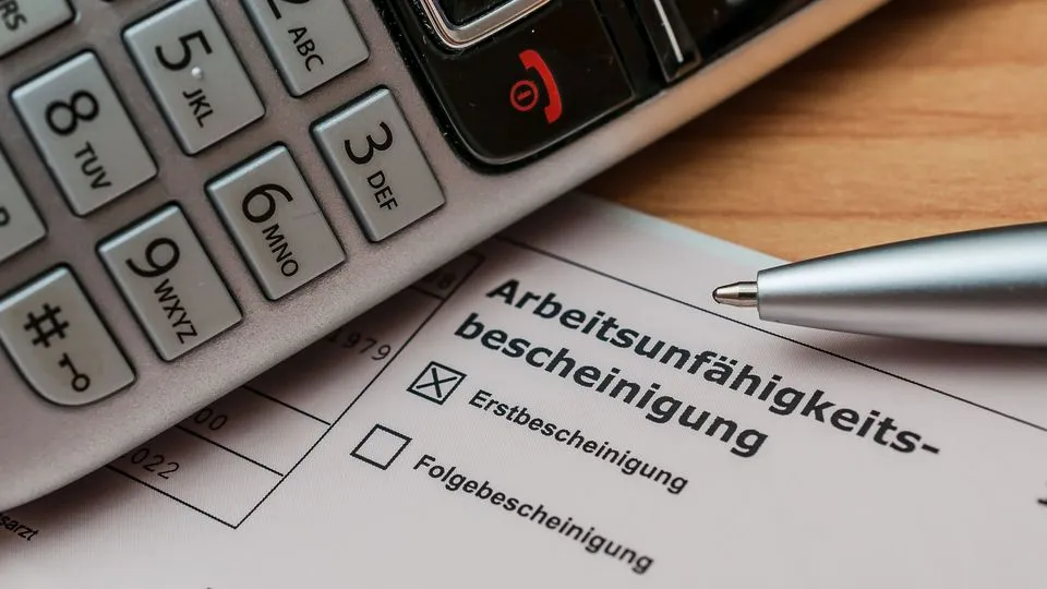 Ein Telefonhörer liegt neben neben einer Arbeitsunfähigkeitsbescheinigung