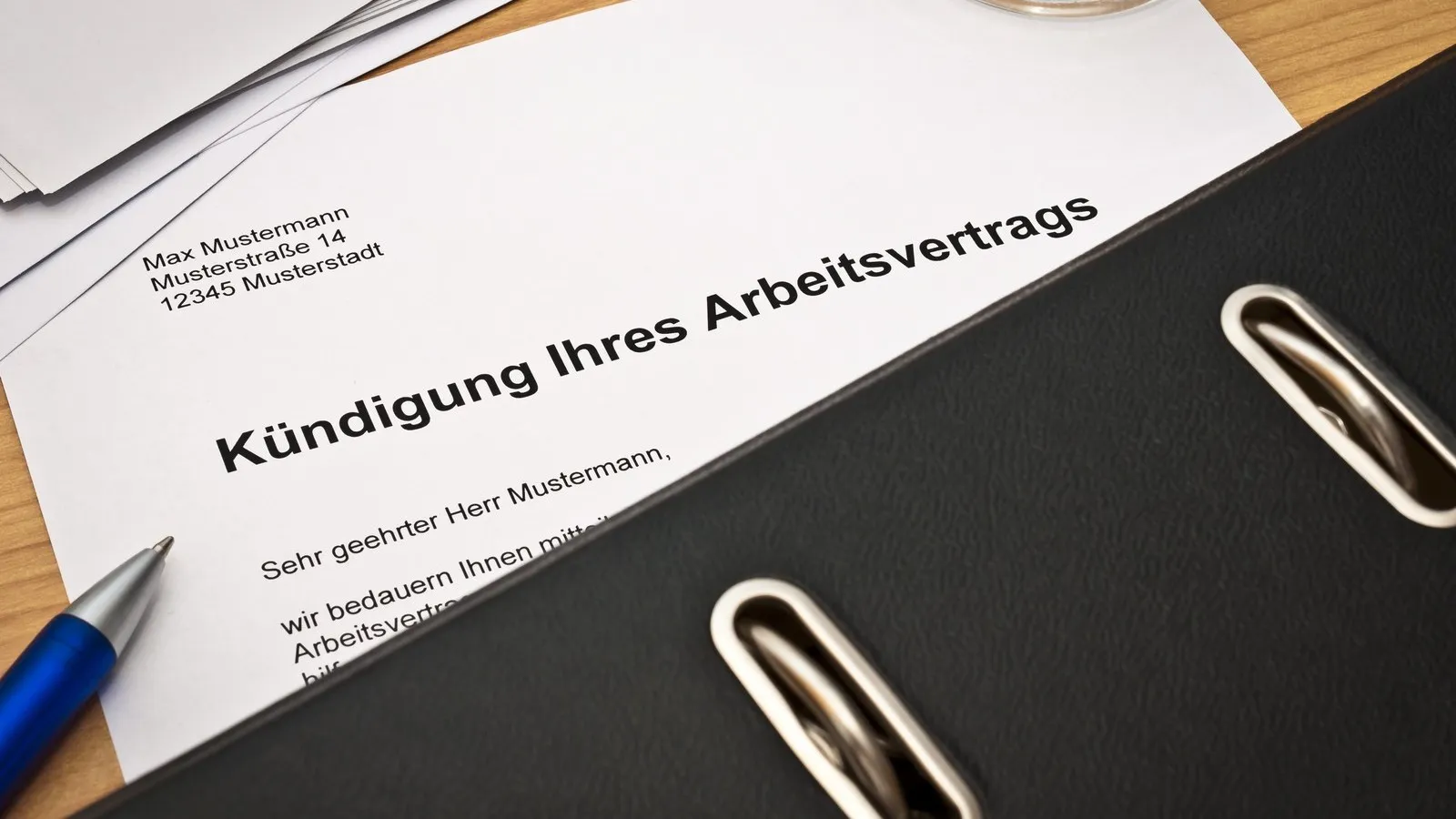 Kündigungsschreiben liegt auf dem Schreibtisch, halb bedeckt von einem schwarzen Ordner.