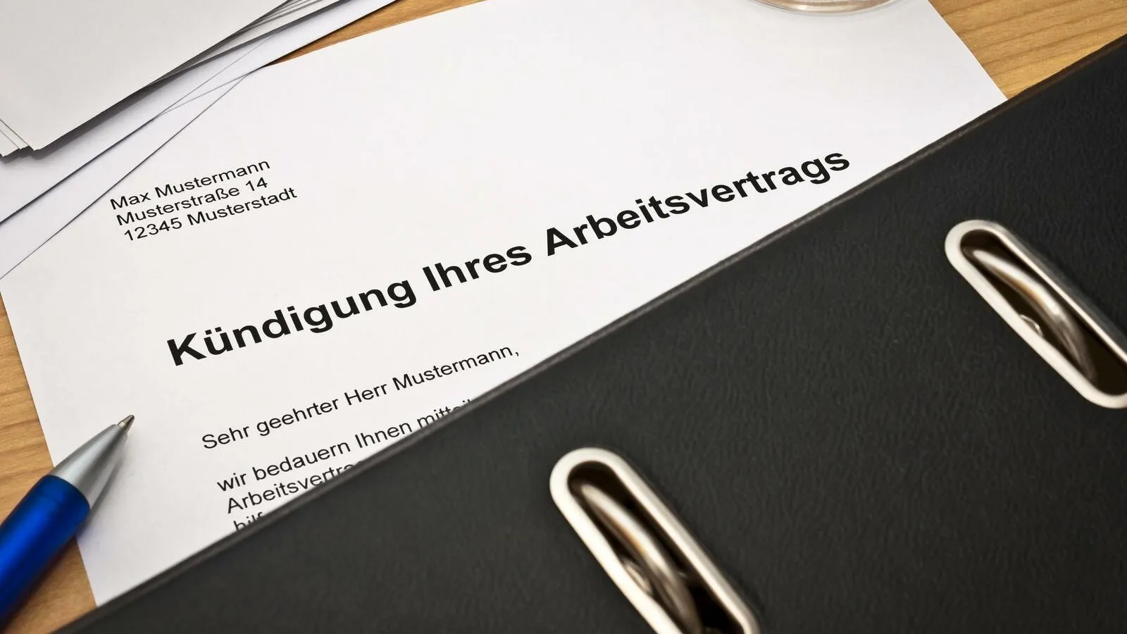 Eine Kündigung eines Arbeitsvertrages, das halbe Blatt ist verdeckt von einem schwarzen Ordner.