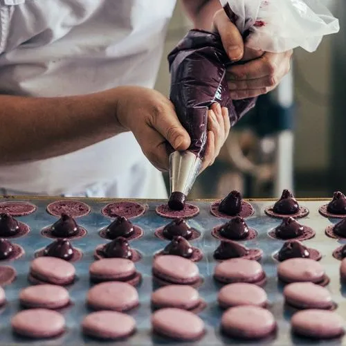 Fokussiert füllt Konditormeister (Maître Pâtissier) Serge Maranzana Macarons Cassis mit einer fruchtigen Ganache.