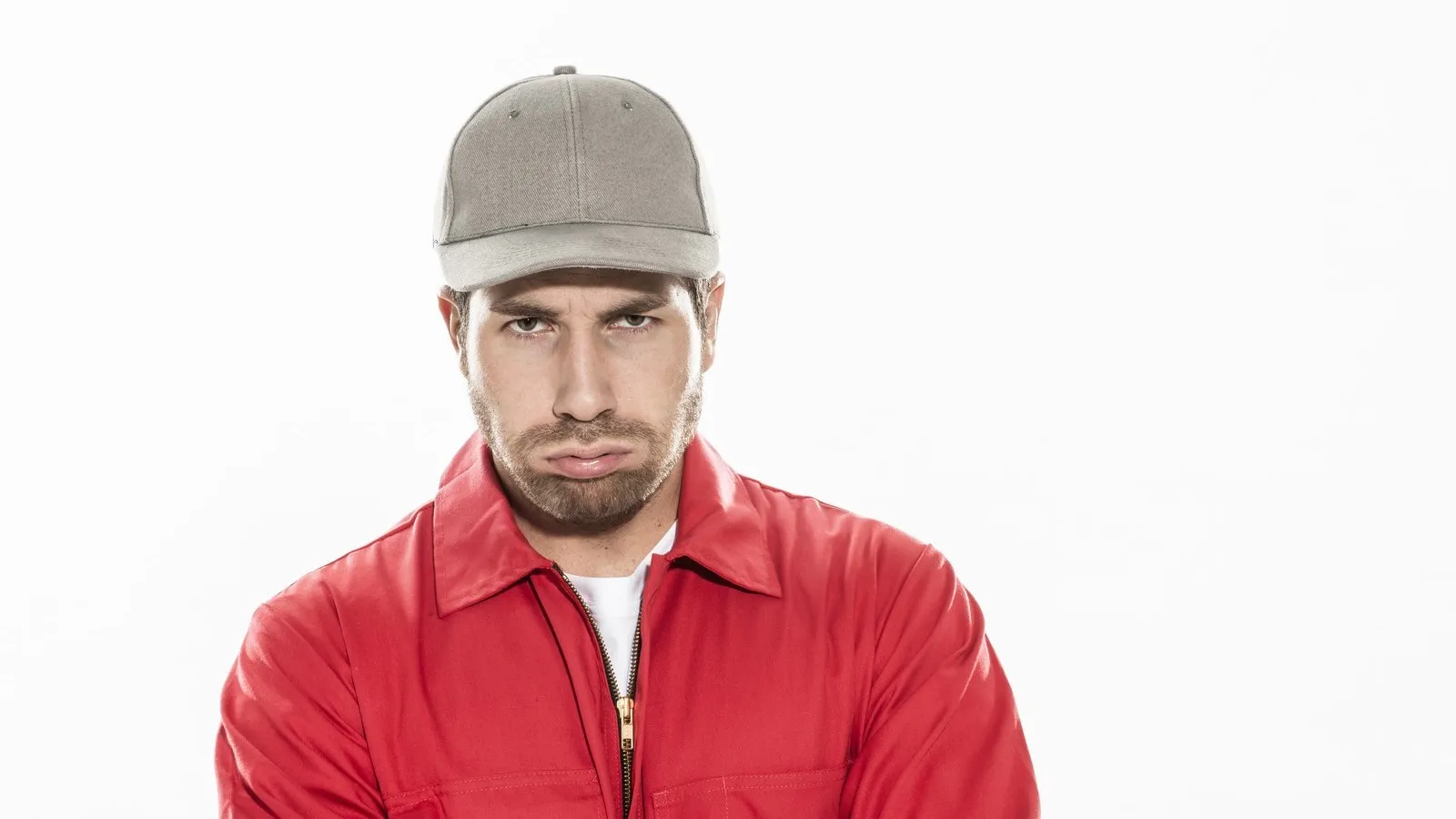 Ein Mann mit einer Cap und einer roten Jacke schaut grimmig.