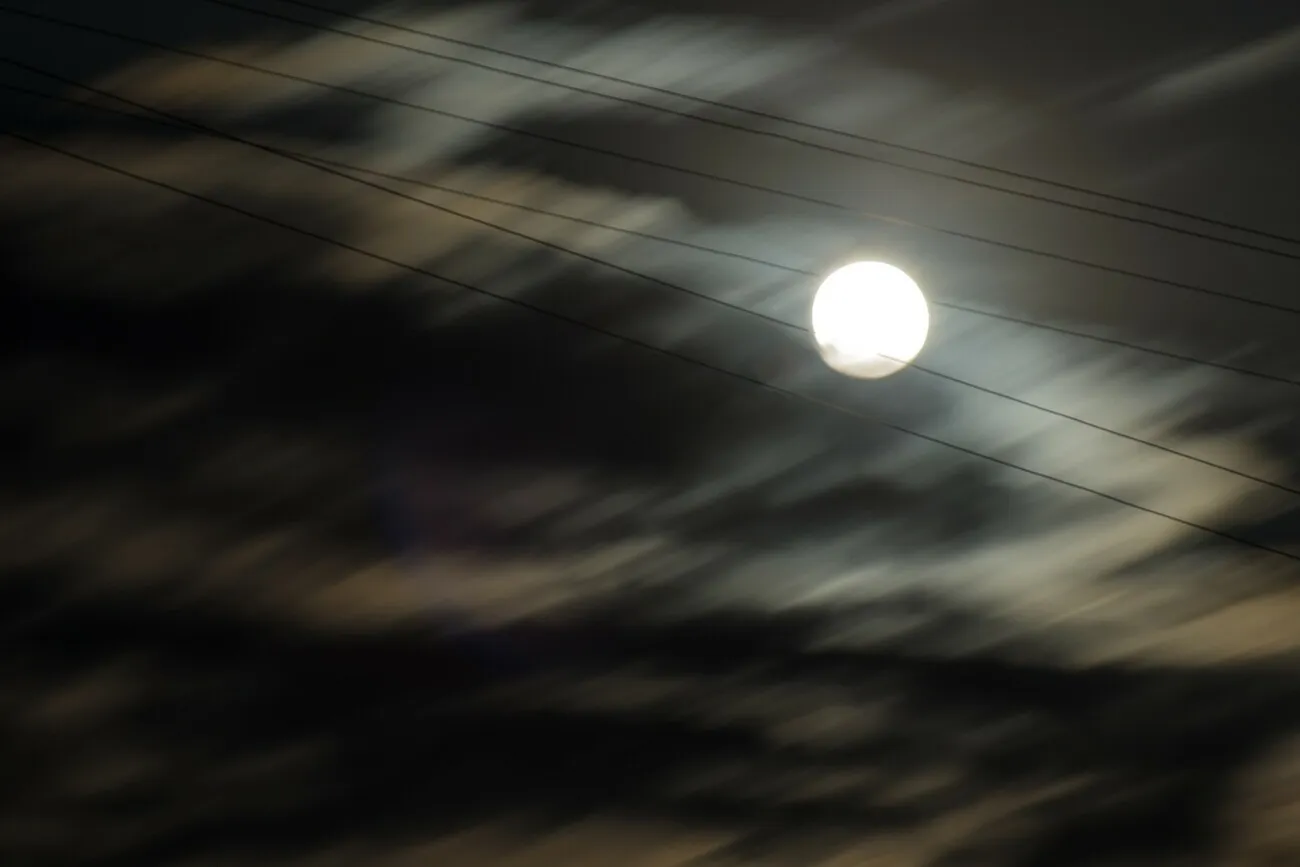 Mond am dunklen Himmel, davor sind Erdseile zu sehen.