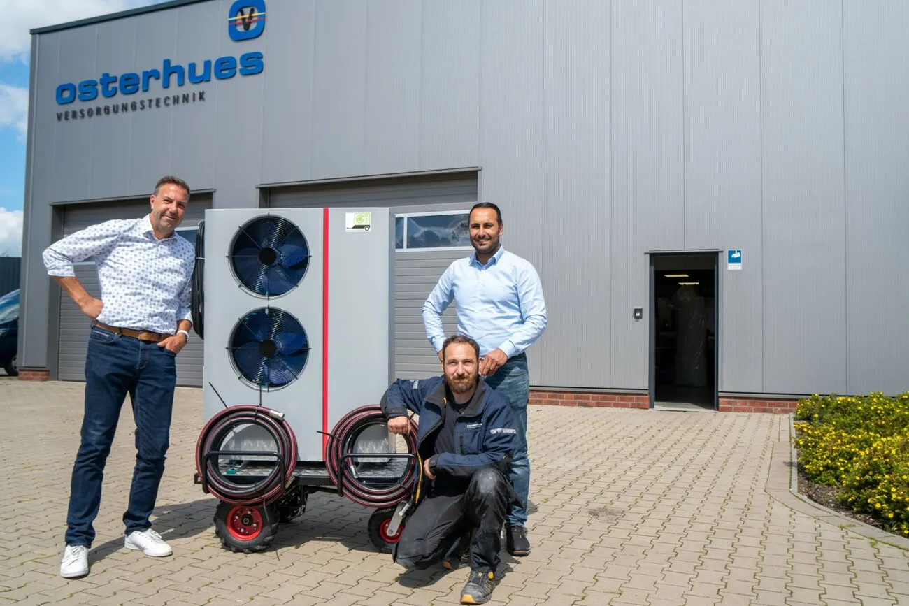 Drei Männer stehen mit der Wärmepumpe draußen für ein Foto: (v.l.r.):  Atec-Vertriebsleiter Heiko Bosse, Osterhues-Anlagenmechaniker und Elektriker Fabian von der Lage sowie Osterhues-Geschäftsführer Ahmet Düman.