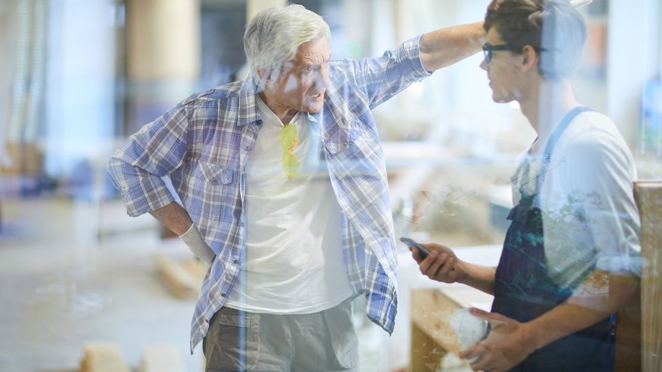 Furious emotional gray-haired mature carpenter foreman pointing with hand and yelling at lazy worker while dressing down him for poor performance in workshop