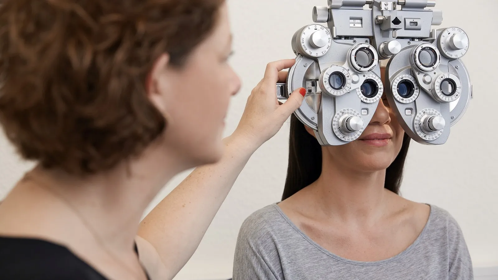 Eine Optikerin führt bei einer Patientin eine Bestimmung des Sehfehlers durch.