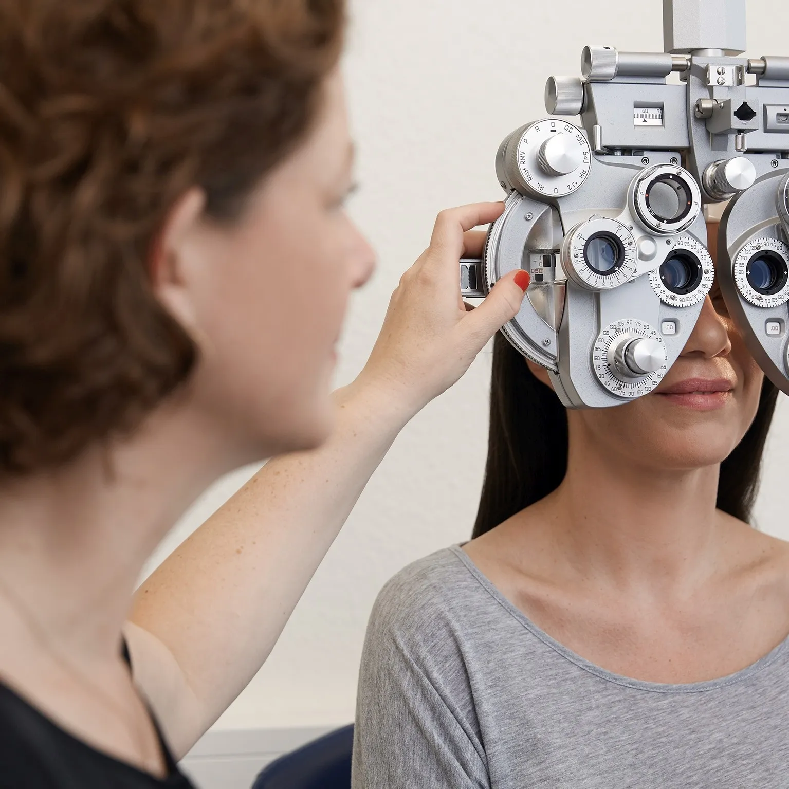 Eine Optikerin führt bei einer Patientin eine Bestimmung des Sehfehlers durch.
