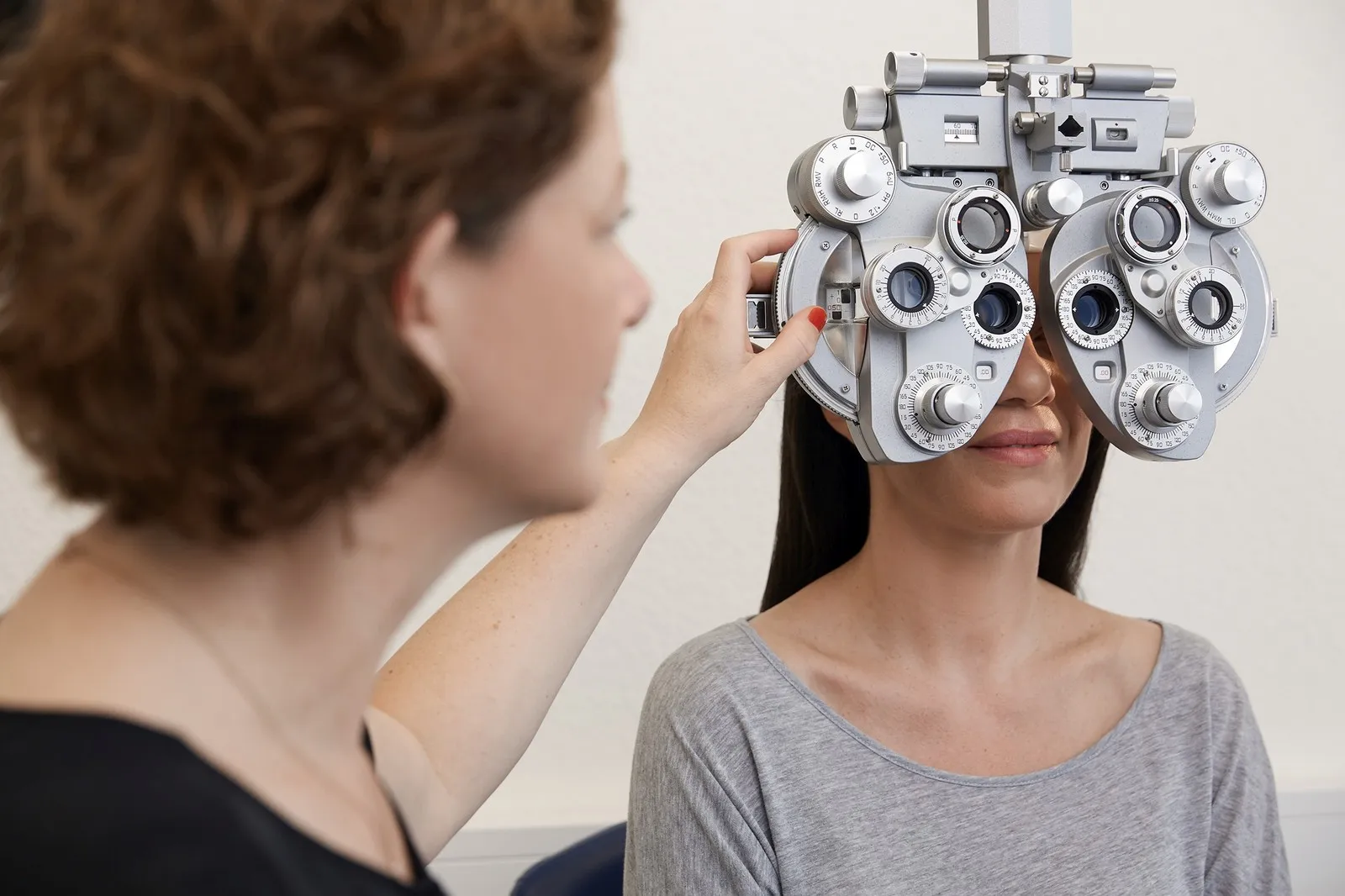 Eine Optikerin führt bei einer Patientin eine Bestimmung des Sehfehlers durch.