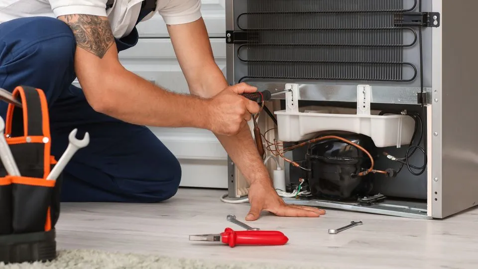 Ein Handwerker repariert einen Kühlschrank.