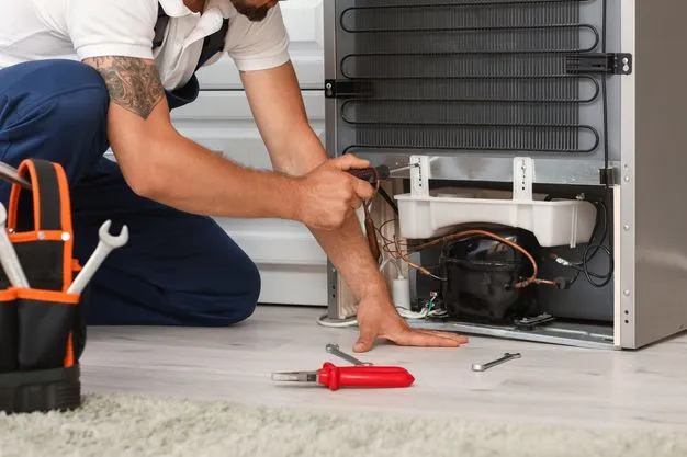 Ein Handwerker repariert einen Kühlschrank.
