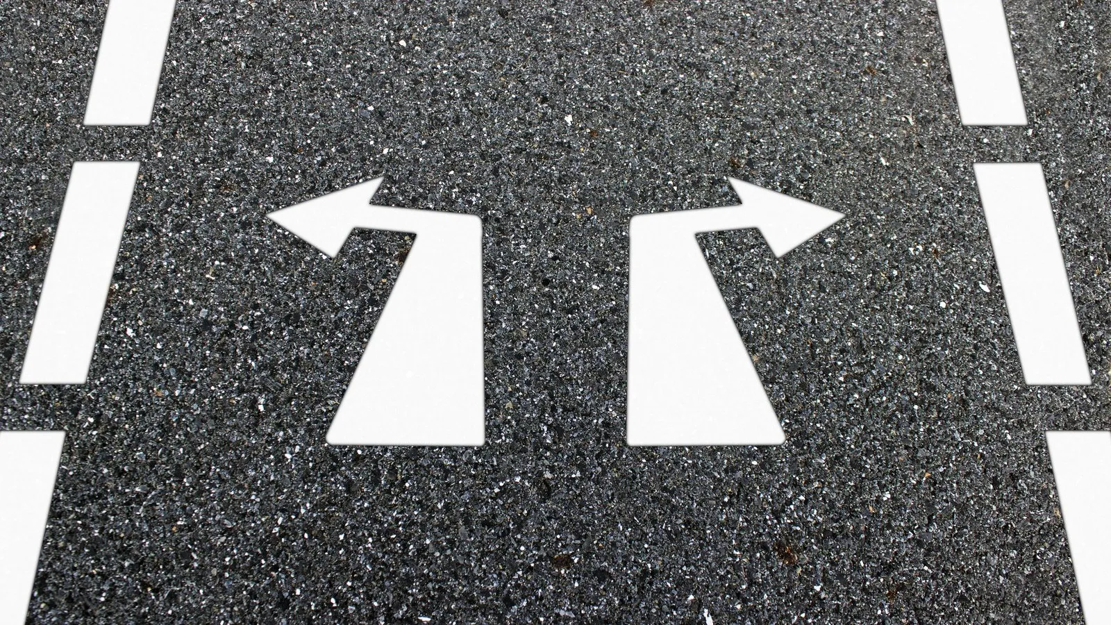 Straße mit zwei weißen Pfeilen nach rechts und links.