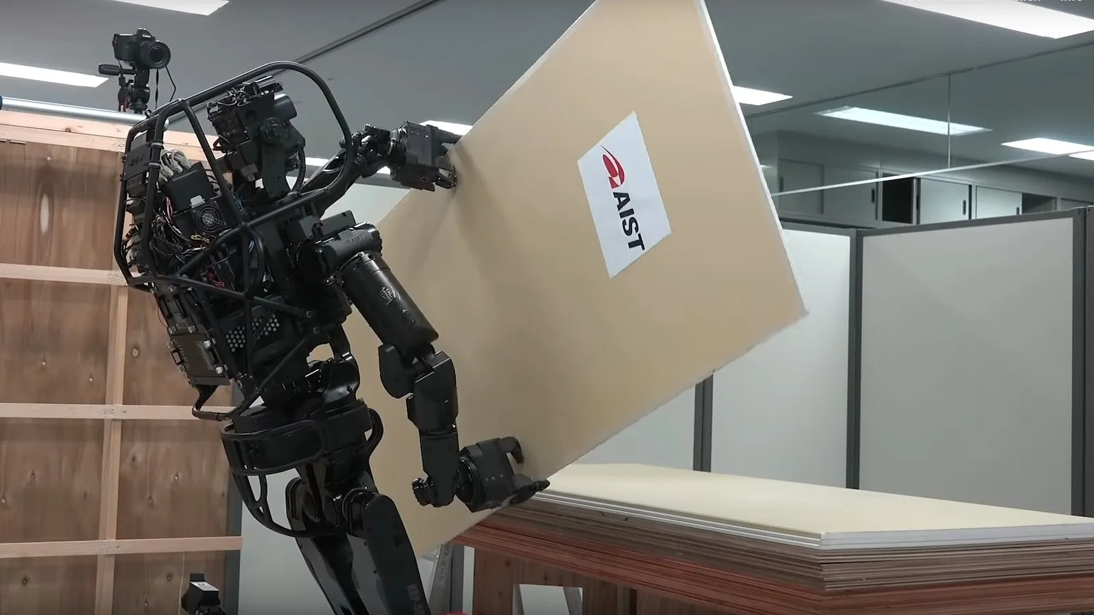Ein schwarzer humanoider Roboter hält eine Trockenbauwand in den Händen.