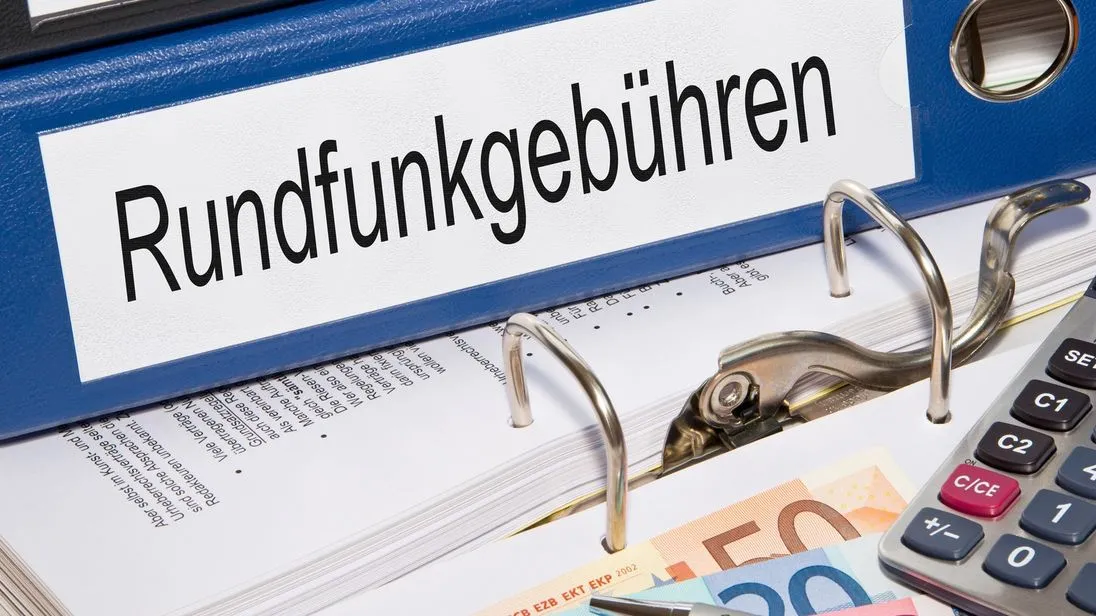 Rundfunkgebühren Ordner liegt auf dem Tisch mit Geldscheinen, Stift und Rechner