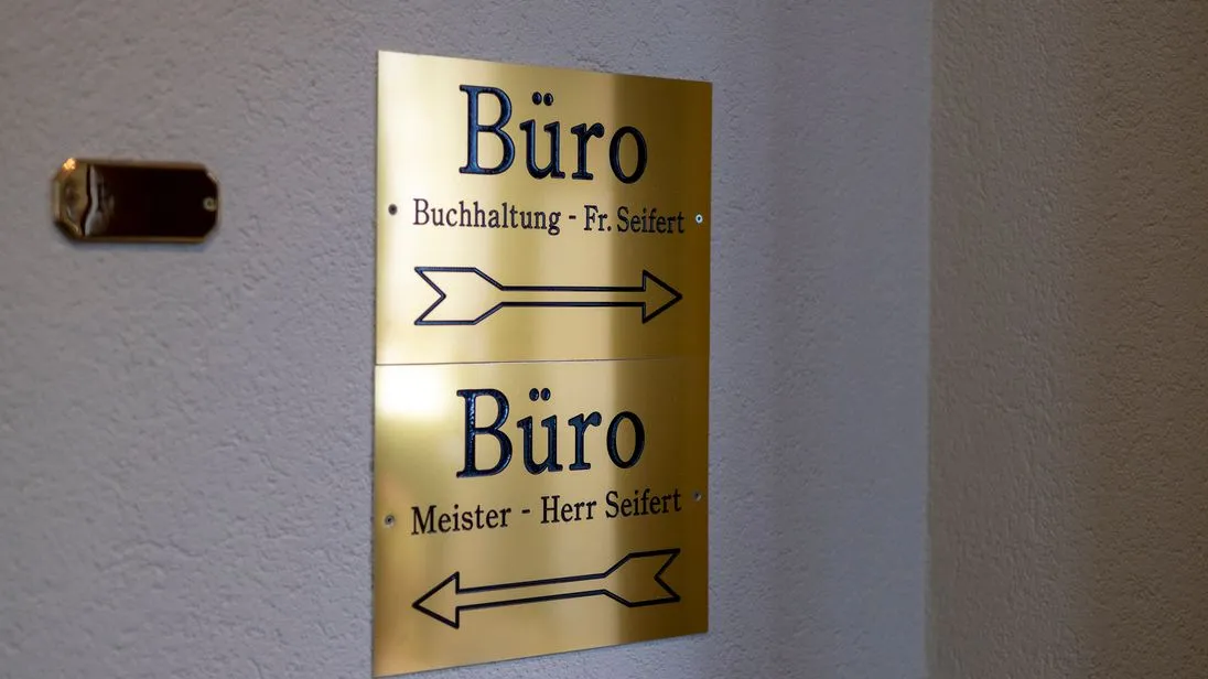 Zwei Messingschilder. Auf dem einen steht "Büro Buchhaltung Fr. Seifert" auf dem andern "Büro Meister- Herr Seifert"