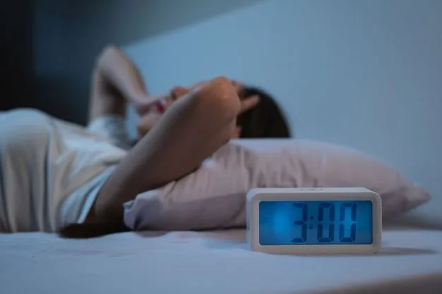 Eine Frau liegt nachts wach im Bett. Ein Wecker neben dem Bett zeigt an, dass es 3 Uhr ist.