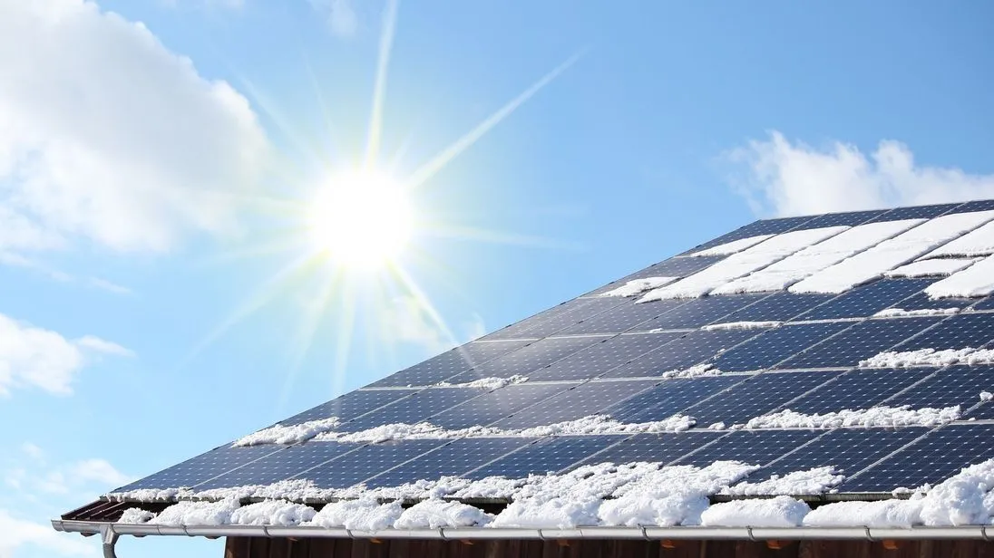 Photovoltaikanlage auf einem Dach, die mit Schnee bedeckt ist.