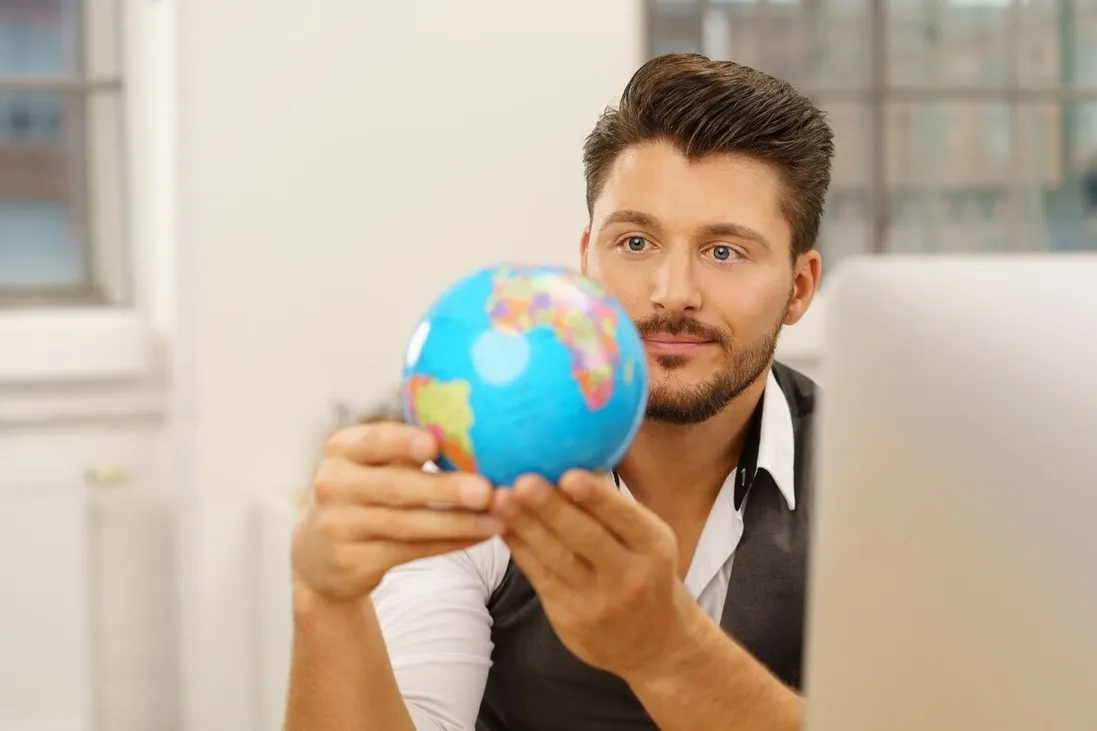 Ein Unternehmer hält einen kleinen Globus in den Händen.